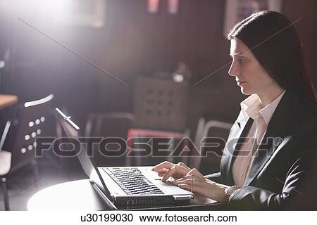 Stock Image - Business woman using laptop in cafe. Fotosearch