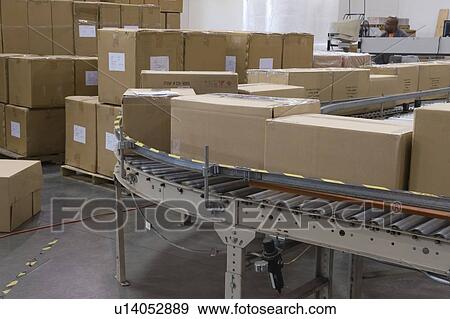 Cardboard boxes on conveyor belt in distribution warehouse View Large Photo Image Stock Photo - Cardboard boxes on conveyor belt in distribution warehouse. Fotosearch