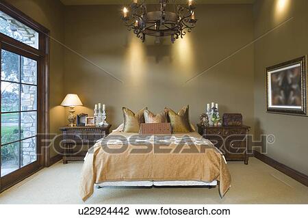 Stock Image - Chandelier hangs over bed in Palm Springs home. Fotosearch