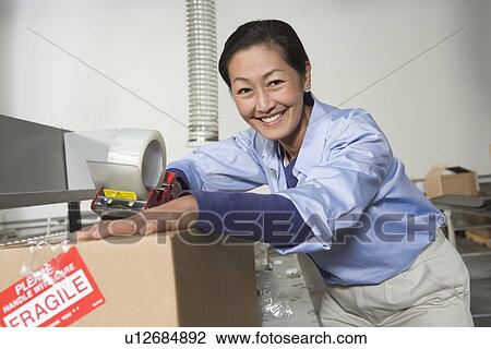 Cheerful Asian woman working in distribution warehouse View Large Photo Image Stock Image - Cheerful Asian woman working in distribution warehouse. Fotosearch