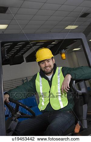 Cheerful man sitting on fork lift truck View Large Photo Image Stock Image - Cheerful man sitting on fork lift truck. Fotosearch