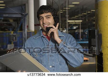 Cheerful man using telephone in factory View Large Photo Image Picture - Cheerful man using telephone in factory. Fotosearch