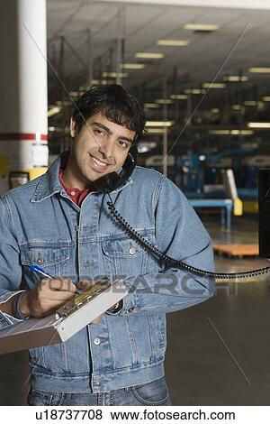 Cheerful man using telephone in factory View Large Photo Image Stock Photo - Cheerful man using telephone in factory. Fotosearch