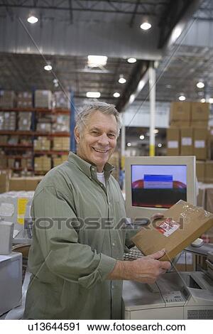 Stock Image - Cheerful man working in distribution warehouse. Fotosearch