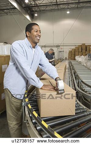 Stock Photo - Cheerful man working in distribution warehouse. Fotosearch