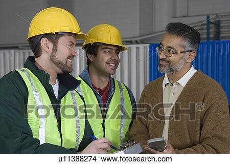 Cheerful men talking in factory View Large Photo Image Picture - Cheerful men talking in factory. Fotosearch