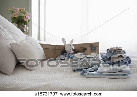 Childrens clothes folded on bed next to suitcase View Large Photo Image Stock Photo - Childrens clothes folded on bed next to suitcase. Fotosearch