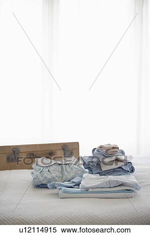 Childrens clothes folded on bed next to suitcase View Large Photo Image Stock Photography - Childrens clothes folded on bed next to suitcase. Fotosearch
