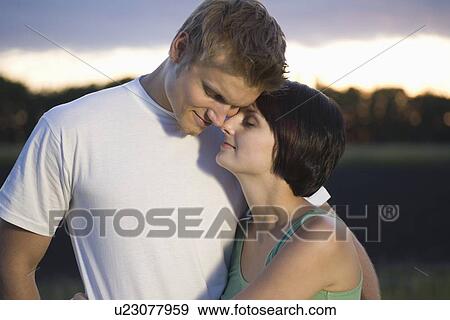 Couple stand embracing with eyes closed in evening light View Large Photo Image Stock Photo - Couple stand embracing with eyes closed in evening light. Fotosearch