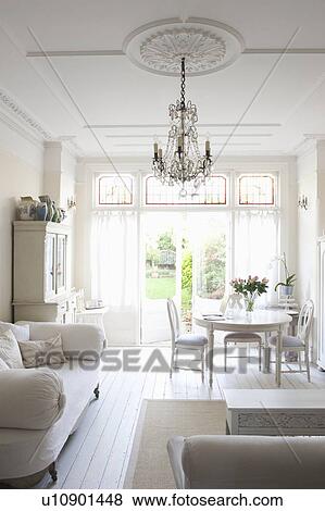 Stock Photo - Daybed with cushions and glass chandelier in white home interior. Fotosearch