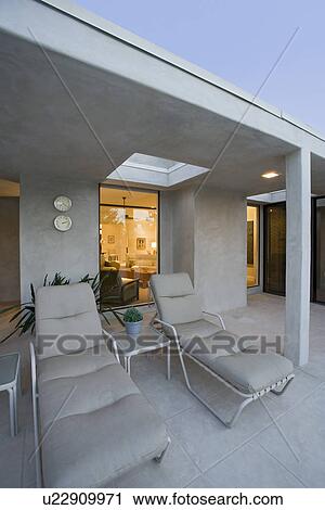 Stock Image - Deckchairs outside modern residence. Fotosearch