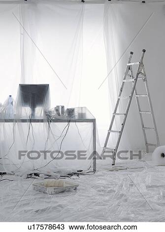 Stock Image - Desk and computer covered in transparent dust sheets in preparation for decoration. Fotosearch