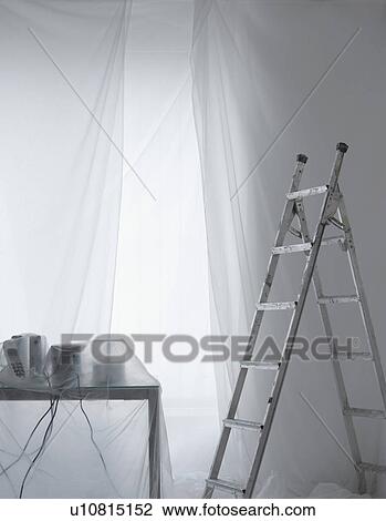 Stock Image - Desk with phones and cables covered in transparent dust sheets with step ladder. Fotosearch
