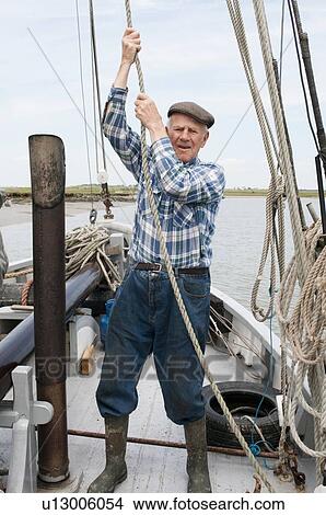 Picture - Elderly fisherman pulling rope on deck. Fotosearch