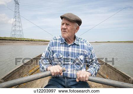 Elderly man rowing a boat on a reservoir View Large Photo Image Stock Photo - Elderly man rowing a boat on a reservoir. Fotosearch