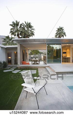 Stock Photo - Empty chair on paved poolside area of Palm Springs home. Fotosearch