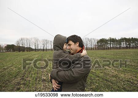 Father embracing son in field View Large Photo Image Stock Photo - Father embracing son in field. Fotosearch