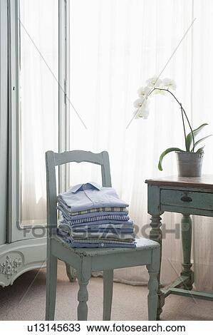 Folded shirts on bedroom chair View Large Photo Image Stock Image - Folded shirts on bedroom chair. Fotosearch