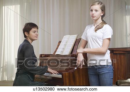 Girl (13-15) singing accompanied by teacher playing piano View Large Photo Image Stock Image - Girl (13-15) singing accompanied by teacher playing piano. Fotosearch
