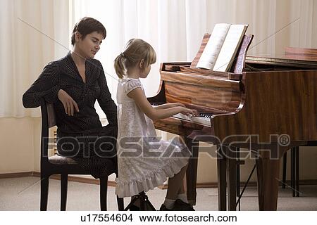 Girl (5-6) playing piano accompanied by teacher View Large Photo Image Picture - Girl (5-6) playing piano accompanied by teacher. Fotosearch