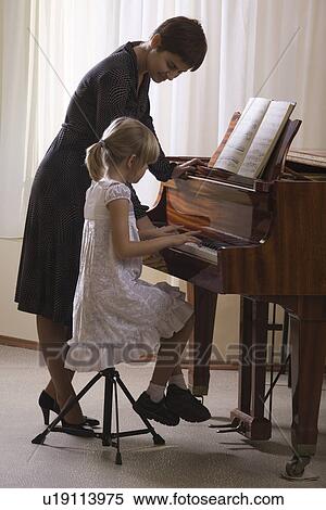 Girl (5-6) playing piano accompanied by teacher View Large Photo Image Stock Photography - Girl (5-6) playing piano accompanied by teacher. Fotosearch