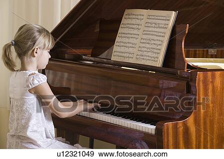 Stock Photo - Girl (5-6) playing piano. Fotosearch