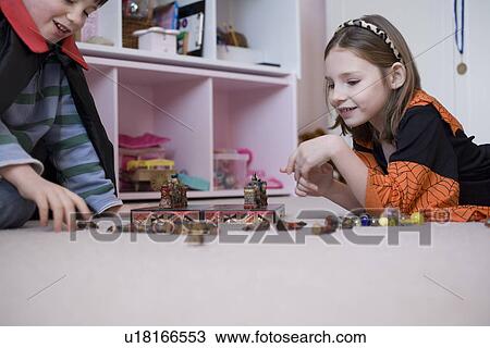 Stock Image - Girl and boy playing board game on floor. Fotosearch