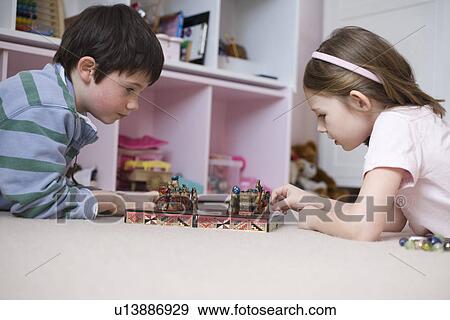 Girl and boy playing board game on floor View Large Photo Image Stock Photo - Girl and boy playing board game on floor. Fotosearch