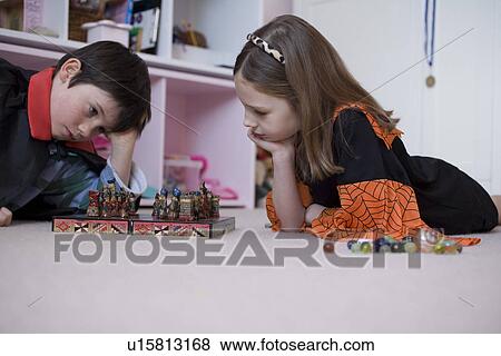 Stock Photo - Girl and boy playing board game on floor. Fotosearch
