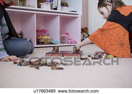 Stock Photo - Girl and boy playing board game on floor. Fotosearch