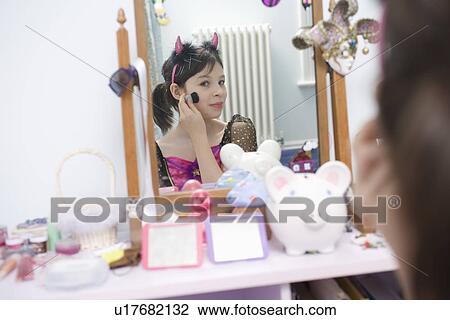Stock Image - Girl applying make-up in mirror. Fotosearch