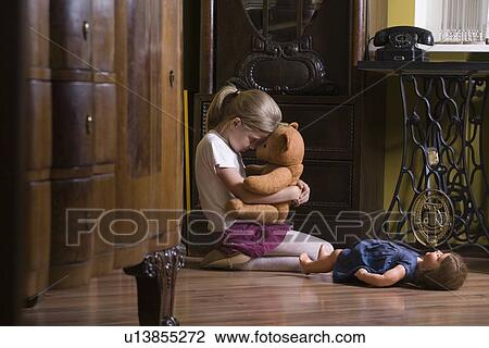 Girl embracing teddy bear on floor in home View Large Photo Image Stock Image - Girl embracing teddy bear on floor in home. Fotosearch