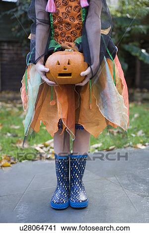 Girl holding pumpkin lantern on garden path View Large Photo Image Stock Image - Girl holding pumpkin lantern on garden path. Fotosearch