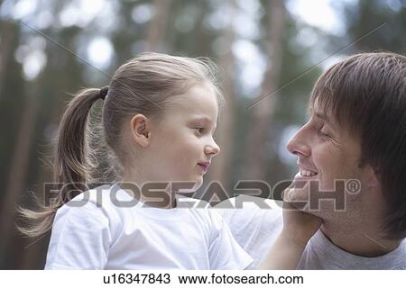 Girl holds hand to man's face in woodland forest View Large Photo Image Stock Image - Girl holds hand to man's face in woodland forest. Fotosearch