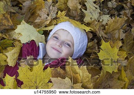 Girl lying in leaves in park View Large Photo Image Stock Image - Girl lying in leaves in park. Fotosearch