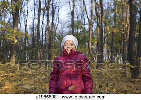 Stock Image - Girl under falling leaves in park. Fotosearch
