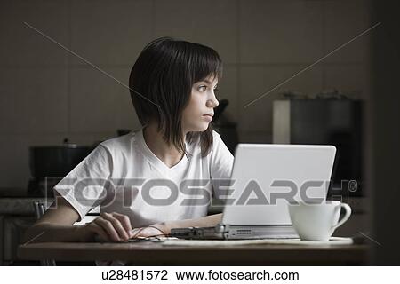 Girl using laptop at kitchen table View Large Photo Image Stock Image - Girl using laptop at kitchen table. Fotosearch