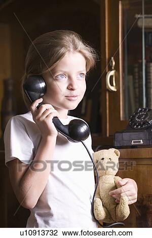 Stock Image - Girl using telephone at home. Fotosearch