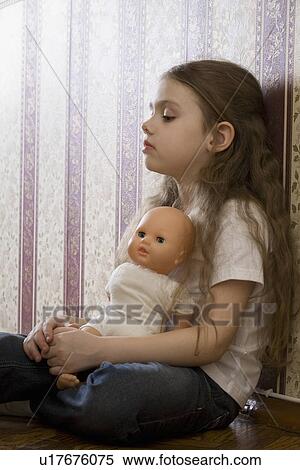 Stock Photography - Girl with doll sitting in home. Fotosearch