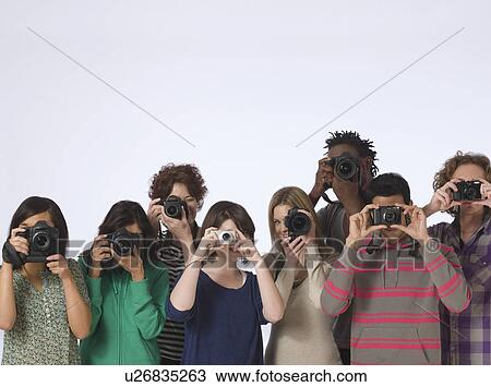 Stock Image - Group of young people making photo straight at camera studio shot. Fotosearch