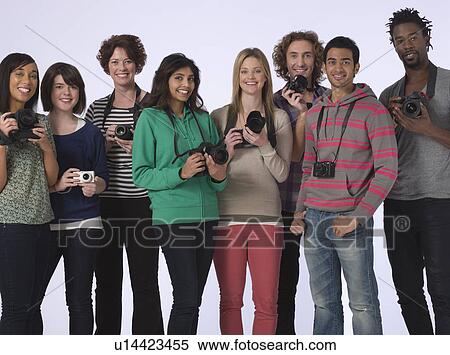 Stock Photography - Group portrait of young people holding cameras studio shot. Fotosearch