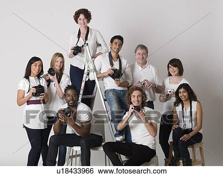 Stock Photograph - Group portrait of young photographers sitting on ladder and chairs. Fotosearch
