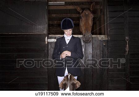 Stock Photo - Horse rider with dog and horse at stable. Fotosearch