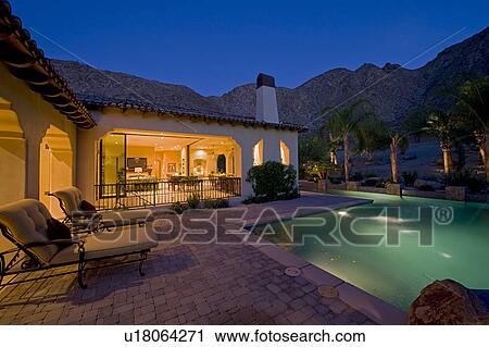 Stock Image - House exterior with swimming pool in backyard at dusk. Fotosearch