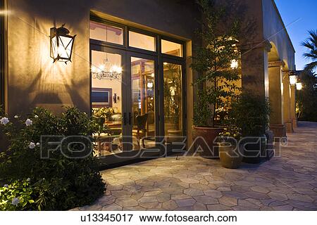 Stock Photo - House exterior with view into living room at dusk. Fotosearch