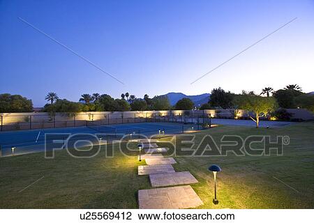 Stock Image - Illuminated lawn and tennis court. Fotosearch