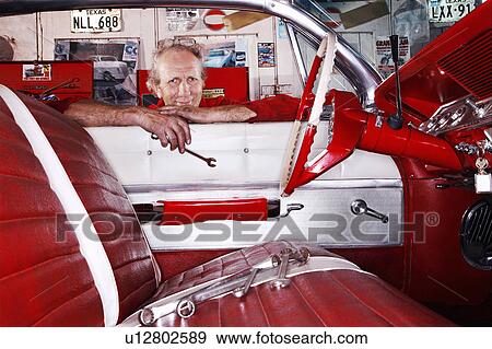 Kent UK portrait of mechanic in garage leaning over car window View Large Photo Image Stock Photo - Kent UK portrait of mechanic in garage leaning over car window. Fotosearch