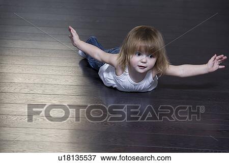 Stock Photo - Little girl lying on floor and doing exercises. Fotosearch