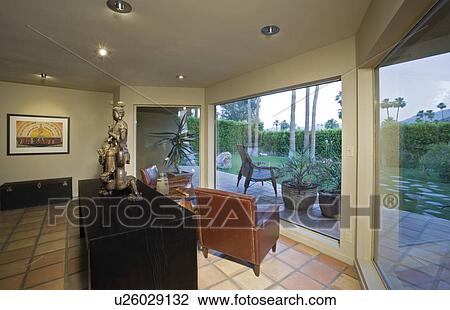 Stock Image - Living room with view of patio and swimming pool. Fotosearch