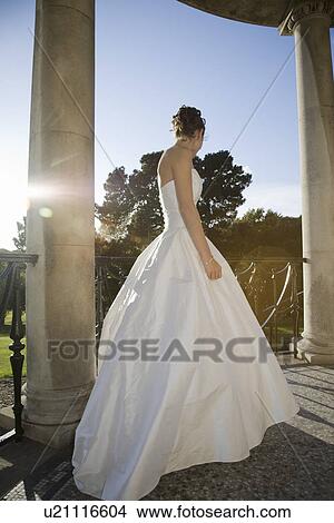 Picture - Low angle view of mid-adult bride standing on balcony. Fotosearch